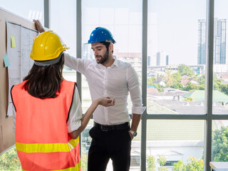 Middle Eastern male engineer in blue helmet and Southeast Asian female engineer in yellow helmet...