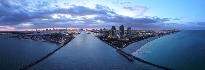 Aerial view of night South Beach coastline. Miami skyline with tropical blue waters panorama....