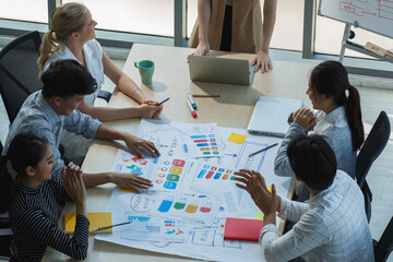 Team of multiethnic colleagues collaborating on marketing plan, analyzing infographics and reports...