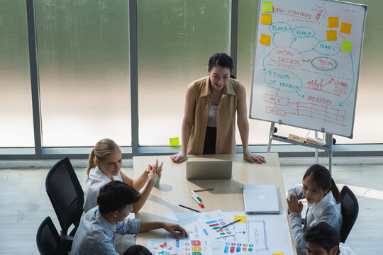 Creative business team planning project strategy, reviewing visual data and brainstorming ideas in bright, modern office environment.