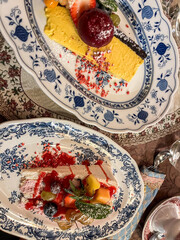 Colorful dessert presentation featuring layered cake topped with fresh fruits and vibrant sauces,...