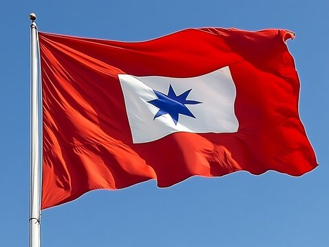 A vibrant red flag with a white star emblem in the wind