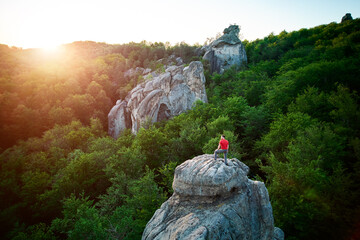 Aerial view of climber standing atop rock formation at Dovbush Rocks in Carpathian mountains,...
