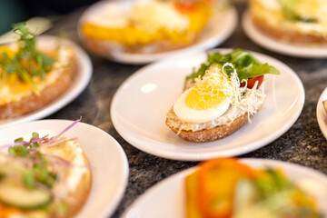 Detail of sandwich at celebration with boiled egg, grated cheese, green salad, butter, mayonnaise and tomato on bread on plates