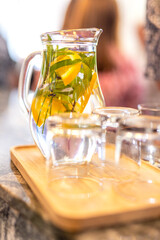 Summer refreshing homemade chilled drink with mint and citrus and ice. Nonalcoholic iced tea, lemonade with lemon. Chilled water with herbs