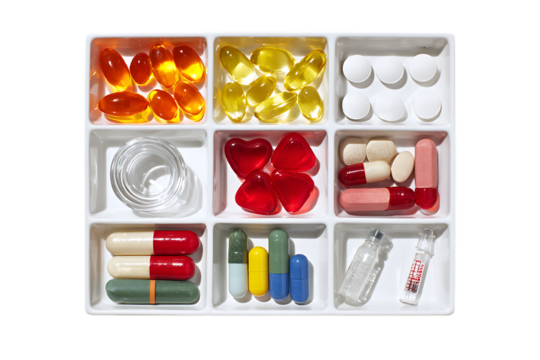Variety of pills and capsules in a weekly pill organizer.