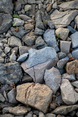 A natural arrangement of grey and brown stones illuminated by soft light, creating a textured earthy background.