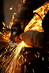 Worker working in industry or factory is holding a cutting stone or grinding stone and sparks are...