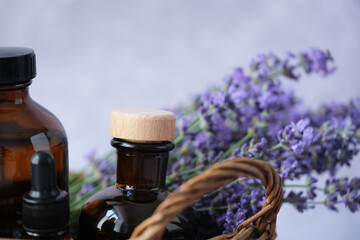 Close up natural beauty product amber glass bottles filled with lavender essential oil in basket with fresh lavender sprigs. Alternative medicine, health and well-being concept.