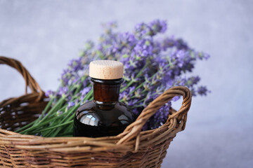 Close up natural beauty product amber glass bottles filled with lavender essential oil in basket with fresh lavender sprigs. Alternative medicine, health and well-being concept.
