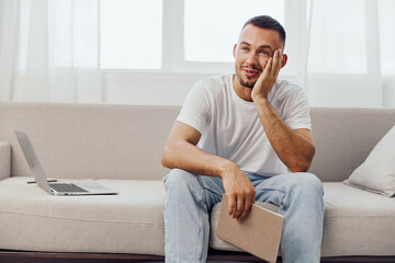 Thoughtful man reflecting on personal challenges while sitting on the couch, embodying themes of...