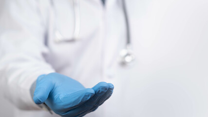 A medical professional in a white coat and blue gloves extends a hand, symbolizing care and...