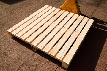 Empty wooden pine pallet with a pallet truck or transpallet in front of a warehouse, logistics and...