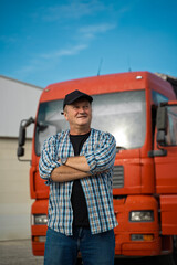 Trucker with cap and arms crossed standing in front of the truck 