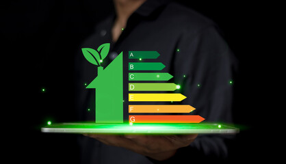 Energy efficiency and green energy concept,man hand holding tablet and looking at house efficiency rating on virtual screen.