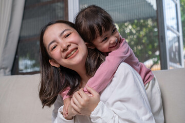 A joyful moment captured of a mother and child sharing a warm embrace, smiling together in a cozy...