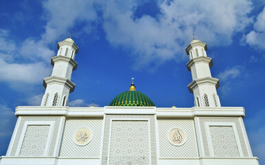 Mosque tower with white clouds in the blue sky