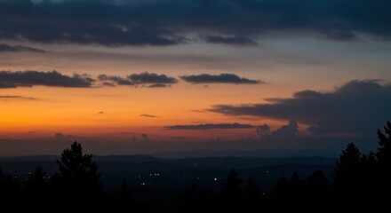 Dramatic sunset sky with orange and blue clouds over silhouetted mountain landscape
