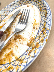 Empty Plate with Sauce Residue, Knife and Fork After Finished Meal on Table