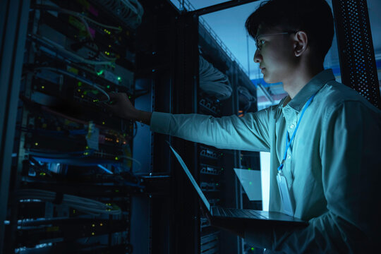 Computer engineer is setting up network in server room,Systems Maintenance Technician,Male engineer working in server room at modern data center