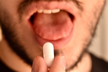 Male hand putting a pill into mouth. Medical treatment, pharmaceutical drug, and health care...