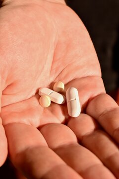 Male hand holding multiple tablets. Symbol of medication use, illness, and recovery process.