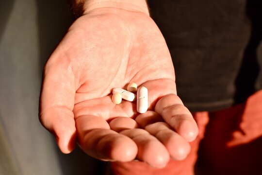 Several pills in a man's hand. Concept of medicine, treatment, and personal healthcare.
