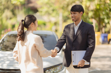 Customers shake hands with car insurance agents after receiving satisfactory compensation after an accident and assessing the damage from a car accident.