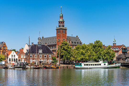 Leer, Germany. Panoramic view from Leda river on city hall, historic weighing house in dutch classical baroque style, tourist harbor and bridge.