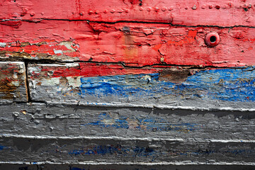 textured wooden surface with weathered, peeling paint in red and blue