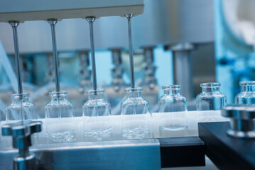 Close up of injection vaccine production machine manufacturing a lot of injections in glass ampoule...