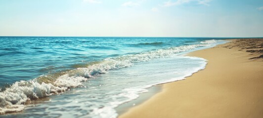 Sandy beach with sand and rolling calm wave of turquoise ocean on Sunny day on blue sky background. Summer concept, copy space. 