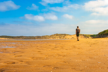 Man strolling on the sand of the beach on a sunny and hot summer day, Cantabria.