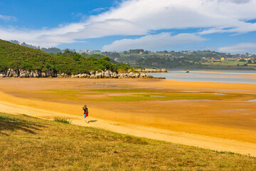 Woman strolling on the sand on a deserted beach in northern Spain, Cantabria,