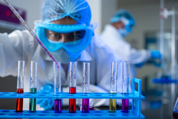 scientist in a lab mixing colorful chemicals in a laboratory. chemist experimenting. science...