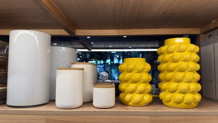 Ceramic jars in various colors on a wooden shelf in a store — aesthetic home decor, modern kitchen organization and functionality of household items