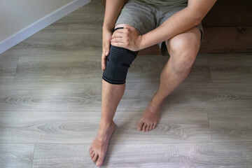 Close up of male leg wearing elastic knee sleeve after strain or trauma. Concept of rehabilitation,...