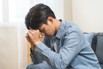 Sad unhappy, alone asian young man headache holding forehead thinking about problem, difficulty,...