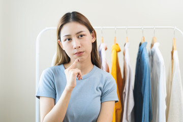Choose clothes, girl try on apparel, worry choosing dress, nothing to wear. Attractive asian young...