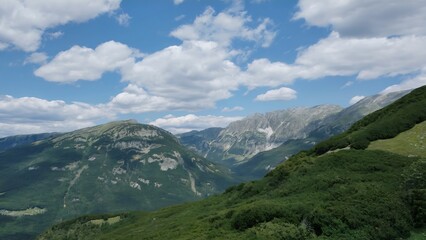 Majestic Mountain Vista with Greenery and Blue Skies Punctured by Fluffy White Clouds