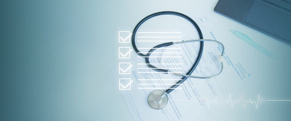 The stethoscope, medical documents, and laptop are on the table in the medical office.