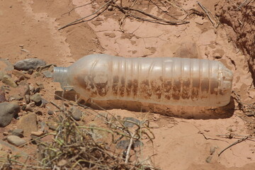 A close-up of a plastic bottle lying on the ground