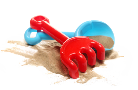 Plastic red rake and  blue shovel, beach toy for kids in sand, isolated on white background