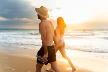 Couple walking on the beach at sunset holding hands