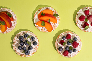 Rice cakes with different types garnish fruits, on green background. Healthy colorful food. Crispy puffed rice cakes with fruit and honey