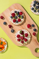 Rice cakes with different types garnish fruits, on green background. Healthy colorful food. Crispy...