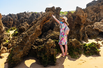Tourist woman touching the rock formations of the beaches of northern Spain, Costa Quebrada, Cantabria.