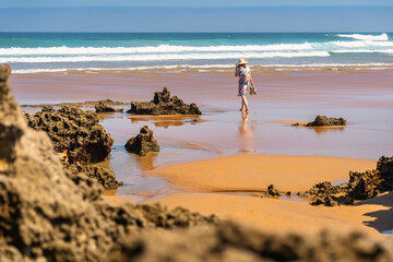 Tourist woman strolling among the rock formations of Liencres beach in northern Spain, Santander.