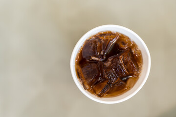 Sweet soda water with ice cubes in paper glass, top view