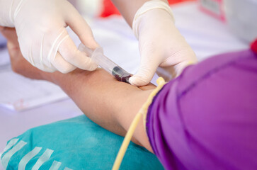Close up nurse pricking needle syringe in the arm patient drawing blood sample for blood test , Health check